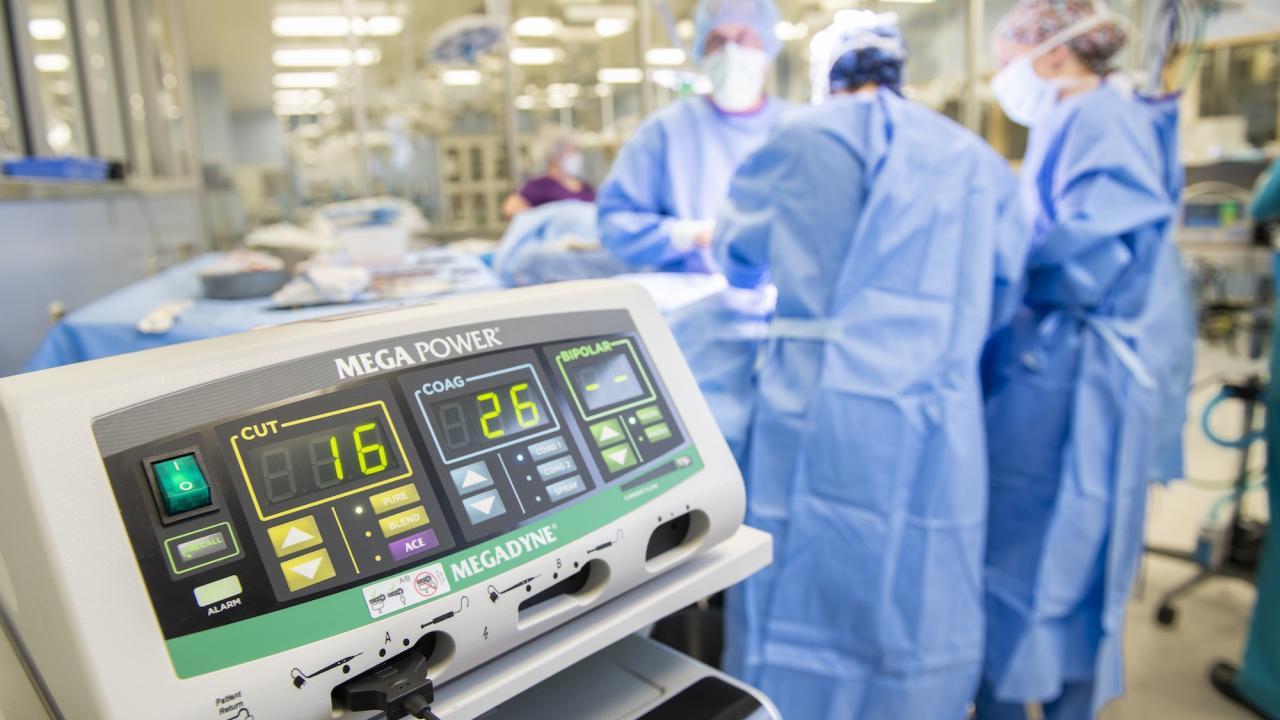 surgeons performing surgery with a cauterizing machine in the foreground